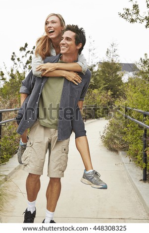 Couple playing piggyback ride in park