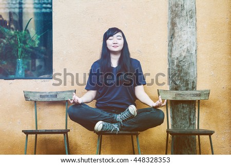 Portrait of beautiful young asian a casual pretty woman meditating on the chair in the house. Vintage style effect picture.