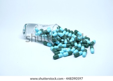 Green and blue antibiotic capsules on clean background.