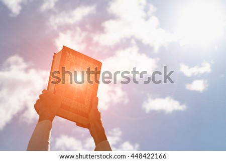 Man's hands holds Koran - holy book of muslims, on blue sky with clouds. With instagram style filter Royalty-Free Stock Photo #448422166