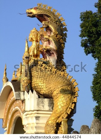 Gold snake statue over an entrance to a temple, Vientiane, Laos.