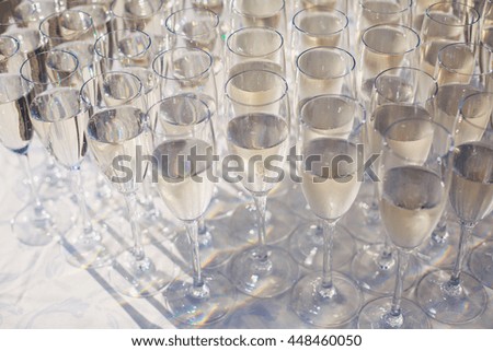 Beautiful row line of gold yellow colored glasses with champagne on a party, on decorated catering bouquet table on open air event, picture with beautiful bokeh
