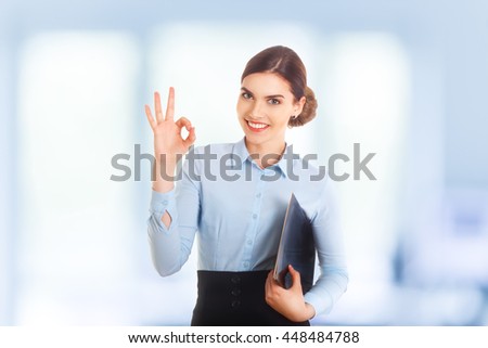 Happy smiling beautiful young businesswoman showing okay gesture, with blank copyspace area for text or slogan