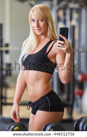 Young sports woman with mobile phone in the gym. Fitness.