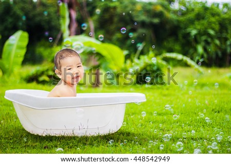 cute baby boy taking water procedures in summer garden