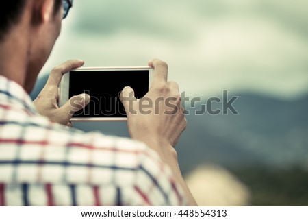 Man hand using cellphone,smartphone,phone to take photo in the park in vintage color tone