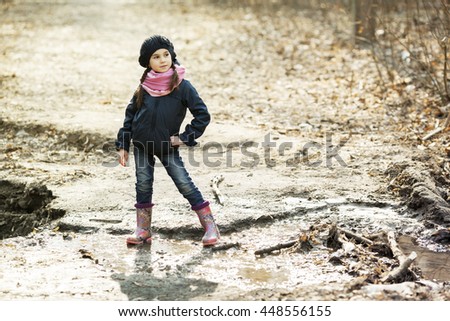 Young girl in rubber boots in the autumn forest