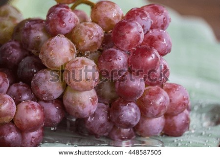 Bunch of red grapes , fresh with water drops. Isolated on banana leaf background . , Close up , Low key photo natural light , Focus sharp specific point 