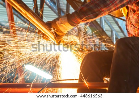 worker cutting metal with grinder. Sparks while grinding iron.