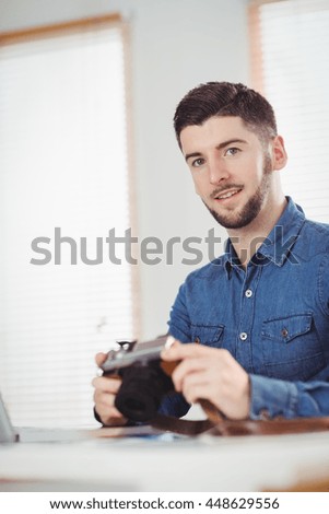 Portrait of man holding camera at office