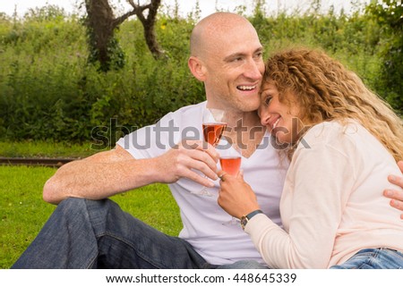 Outdoor picnic by couple that are enjoying a glas of Sparkling wine while relaxing in nature - Lifestyle image showing a mature and happy couple drinking Sparkling wine/Champagne.