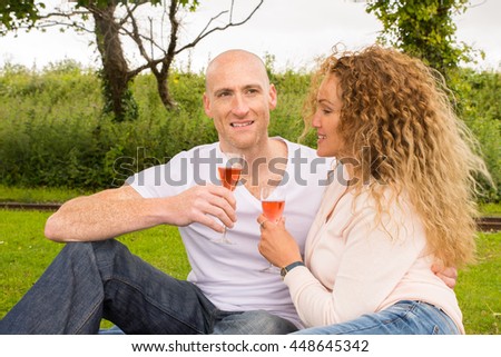 Outdoor picnic by couple that are enjoying a glas of Sparkling wine while relaxing in nature - Lifestyle image showing a mature and happy couple drinking Sparkling wine/Champagne.
