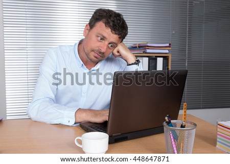 Serious doubtful businessman thinking and looking sideways sitting in a desk at office Royalty-Free Stock Photo #448647871
