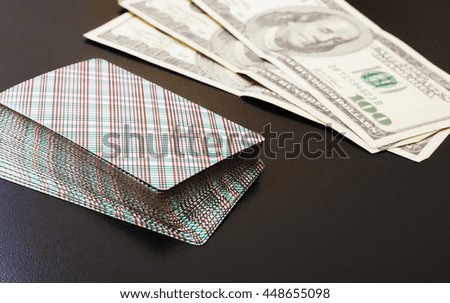 playing cards and hundred-dollar bills on a black background.side view