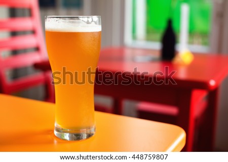Craft beer pale ale glass in hipster pub. Colorful background and copy space. Shallow depth of field