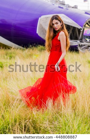  Picture of Beautiful Thai girl with long curly hair in a long red dress posing in the grass field
