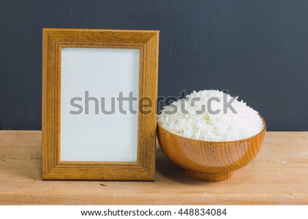 Photo old wood frame with cooked rice in bowl on old wooden table, black background. Emphasizing copy space for write text.