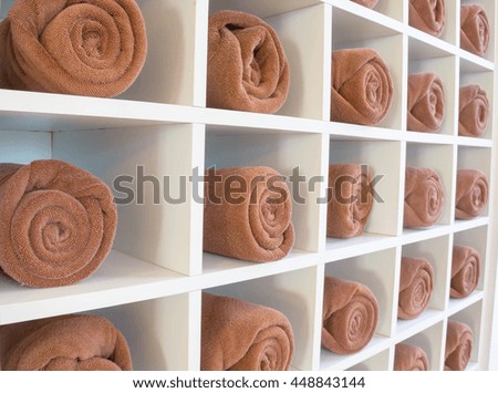 rolled up brown spa towels on wooden cabinet