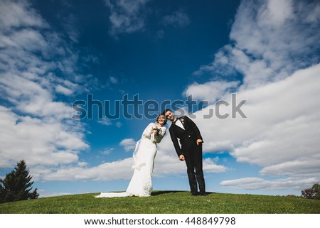 A funny picture of newlyweds leaning to each other on the green hill