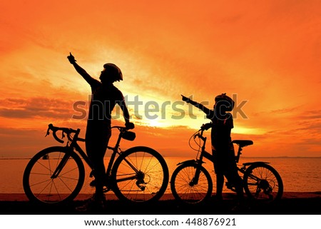 Biker family silhouette at the beach at sunset.