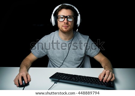 technology, gaming, let's play and people concept - young man or hacker in headset and eyeglasses with pc computer playing game and streaming playthrough or walkthrough video over black background Royalty-Free Stock Photo #448889794