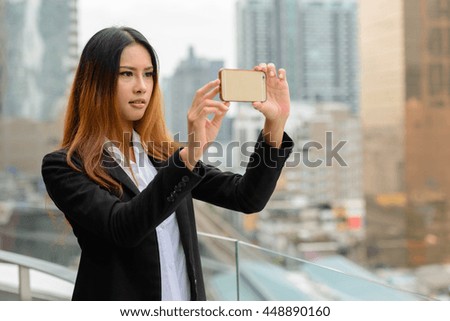 Beautiful Asian businesswoman taking picture outdoors