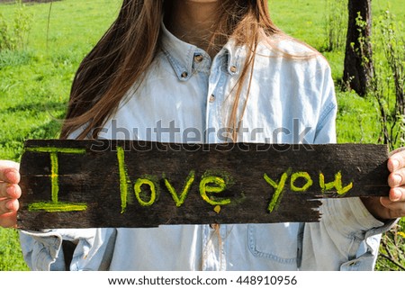 Beautiful young happy artist woman posing with i love you sign in field