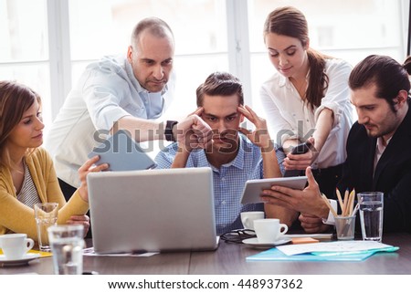 Irritated businessman in between coworkers showing technologies in creative office Royalty-Free Stock Photo #448937362