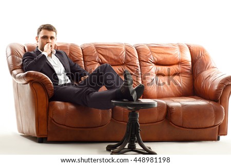 Portrait of handsome thinking businessman  holding his chin sitting on the couch isolated on white