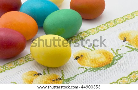 Yellow Easter eggs lie on embroidered canvas  picture with chickens