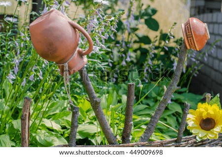 Ancient traditional Ukrainian clay pot standing on a cut tree in summer garden
