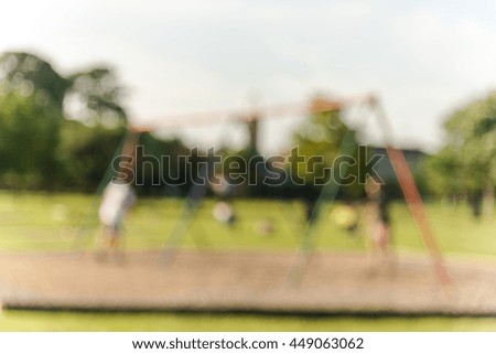 Defocused, blurred motion abstract background of children playground activities in public park at sunset in Houston, Texas. Child swings on modern playground, child and parents doing activity together