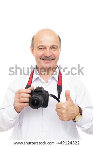 elderly man is holding a camera and shows thumb up