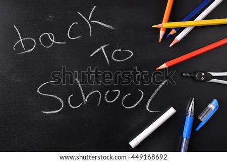 Back to school concept written with chalk on a blackboard and school supplies. Top view