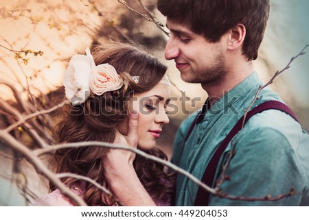 Couple of lovers is embracing under a tree during the early spring season - people, love, mirror and fireplace and nature concept. Image released. Toned
