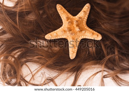 Sea Star On Child Hairs On White Paper Background Close Up.