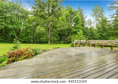 View of wooden walkout deck with patio area. Backyard garden with green lawn.
