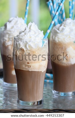 Root beer floats with whipped cream and colorful party straws. Extreme shallow depth of field with focus on center glass.