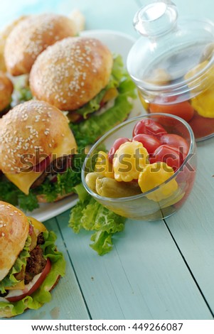 A bowl of pickles with some burgers.