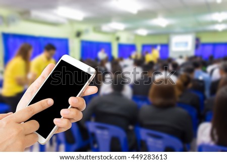 woman use mobile phone and blurred image of people are studying in classroom,people meeting in conference room