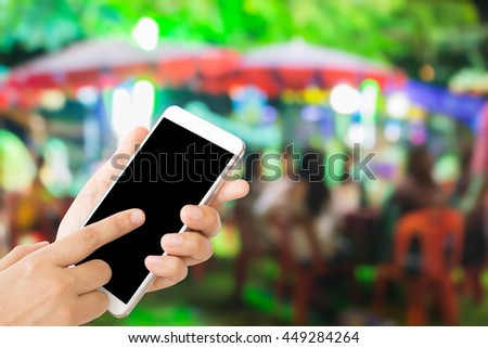 woman use mobile phone and blurred image of people in outdoor party at night