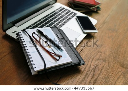 Layout of working place with wooden table and laptop laying,copy space ,Place of work. comfortable working space, internet laptop headphone smart phone notepad paper pen eyeglasses mouse laying on it
