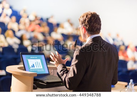Speaker at Business Conference with Public Presentations. Audience at the conference hall. Entrepreneurship club. Rear view. Horisontal composition. Background blur. Royalty-Free Stock Photo #449348788