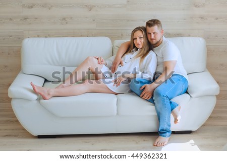 Couple with pregnant woman relaxing on sofa together