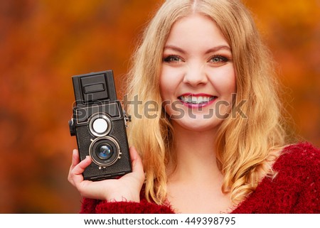 Portrait of pretty smiling woman in fall forest park with old vintage camera. Happy gorgeous young girl passionate photographer. Autumn winter photography.