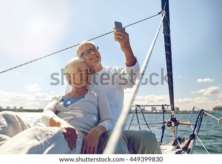 sailing, technology, tourism, travel and people concept - happy senior couple taking selfie with smartphone on sail boat or yacht deck floating in sea