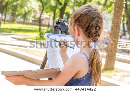 young happy child girl drawing a picture outdoors, kid painting