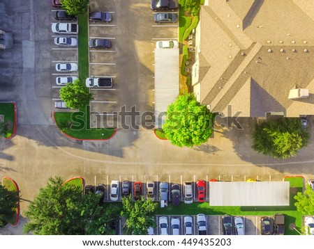 Aerial view of apartment garage with full of covered parking, cars and green trees of multi-floor residential buildings in Houston, Texas, US at sunset. Urban infrastructure and transportation concept