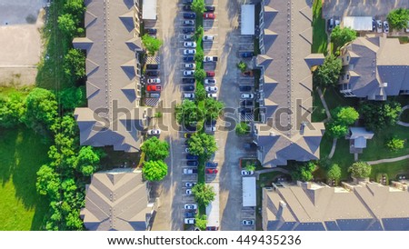 Aerial view of apartment garage with full of covered parking, cars and green trees of multi-floor residential building at sunset in US. Urban infrastructure and transportation concept. Panorama view.
