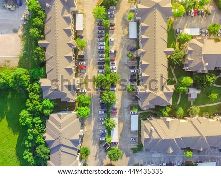 Aerial view of apartment garage with full of covered parking, cars and green trees of multi-floor residential buildings in Houston, Texas, US at sunset. Urban infrastructure and transportation concept